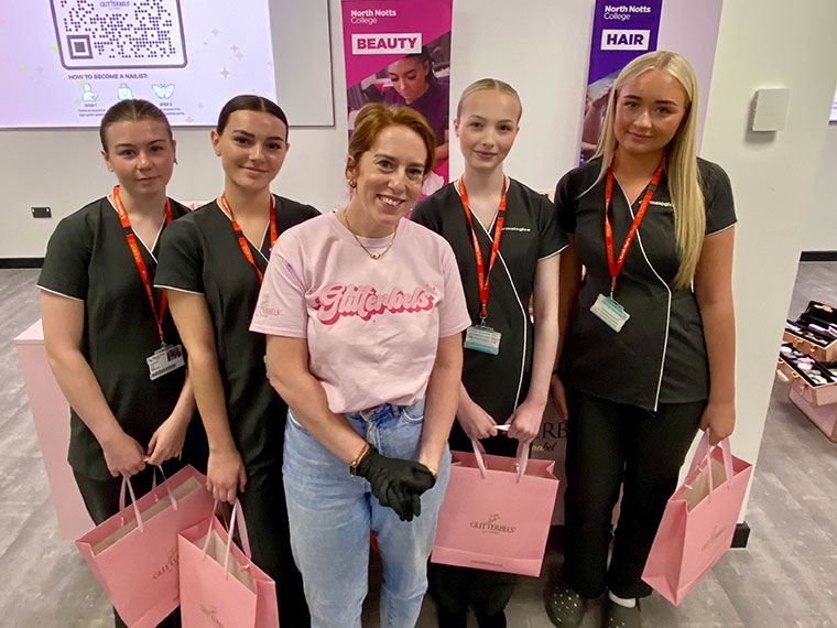 A lady stood with four students stood holding pink Glitterbels goody bags