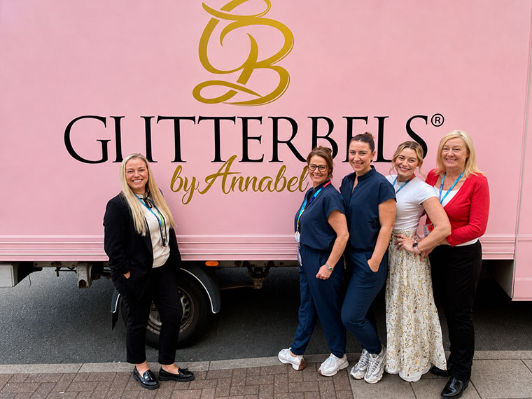 Staff members standing next to a Glitterbels sign