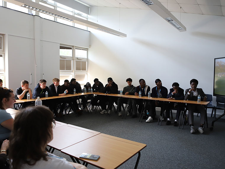 A large group of students all sat behind a long row of desks
