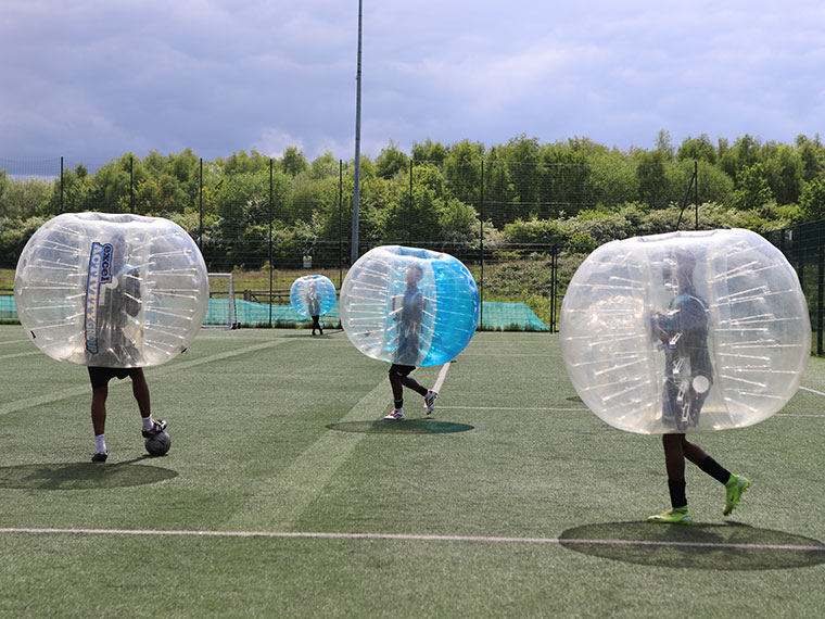 People zorbing on an outdoor football field