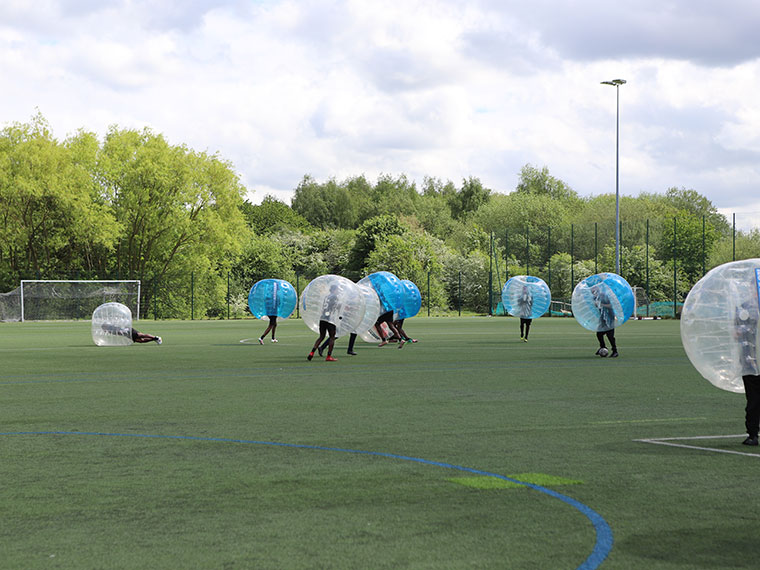 People zorbing on an outdoor football field