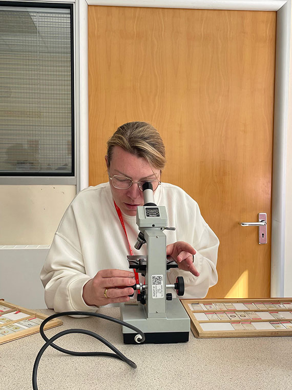 A person sat at a table looking into a microscope