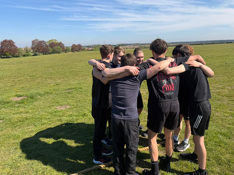 A group of people huddling together outside on the grass
