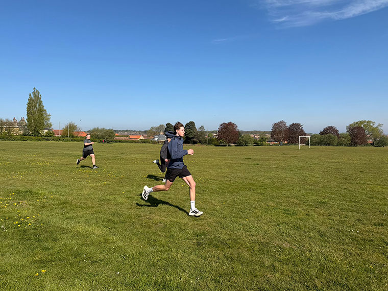 Someone running across grass, taking part in a race