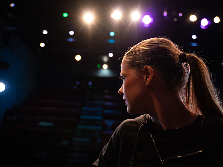 A close up of the side of someone's head as they look out towards the audience and the lights