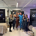 Six people stood together with two beauty therapy beds next to them and two a-training pull up banners