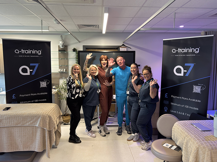 Six people stood together with two beauty therapy beds next to them and two a-training pull up banners