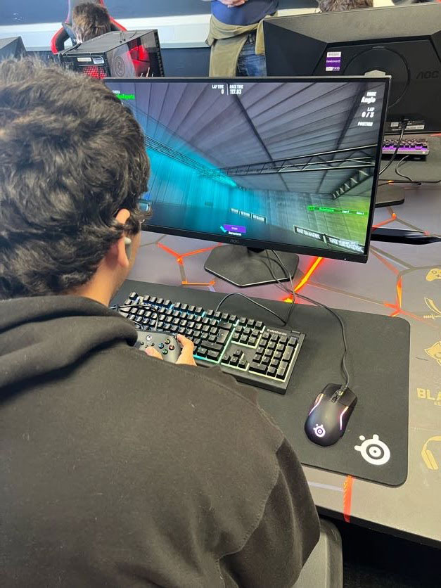 Looking at the back of someone sat in front of a computer screen, keyboard and mouse
