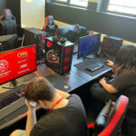 Two people sat on gaming chairs in front of computer screens