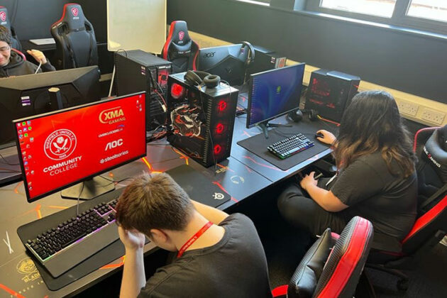 Two people sat on gaming chairs in front of computer screens