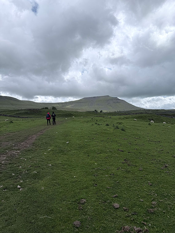 Green grass and two hills inthe background, two people in the distance walking away