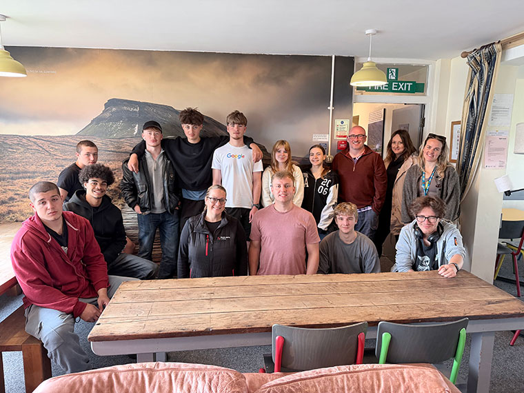 A group of people around a table inside a room, some people seated some standing