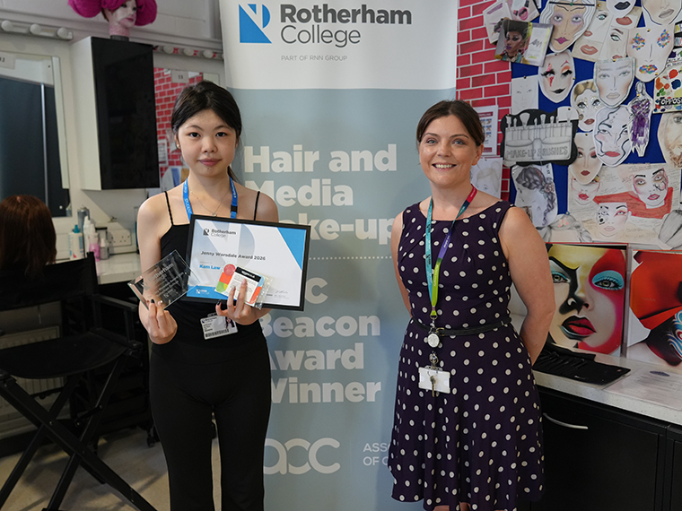 Two females one wearing black top and trousers and holding a certificate, the other wearing a polka dot dress