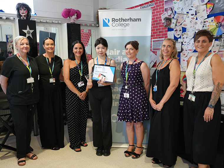 Seven females stood in a line in front of a Rotherham College pull up banner, the person in the centre is holding a certificate