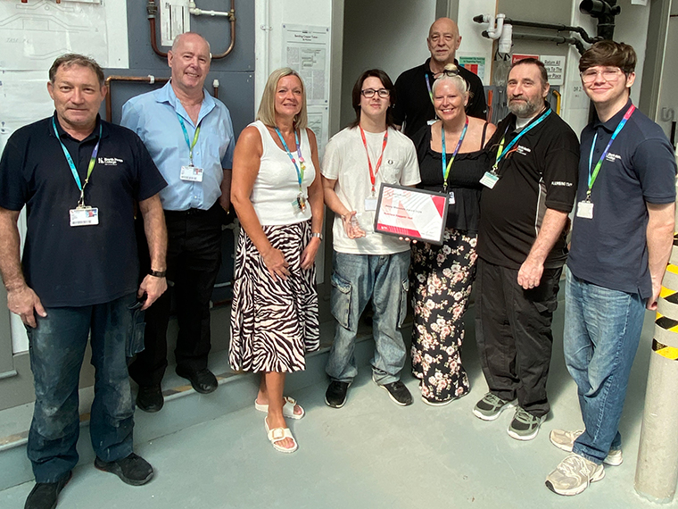 Eight people stood together, the person in the middle is holding a certificate