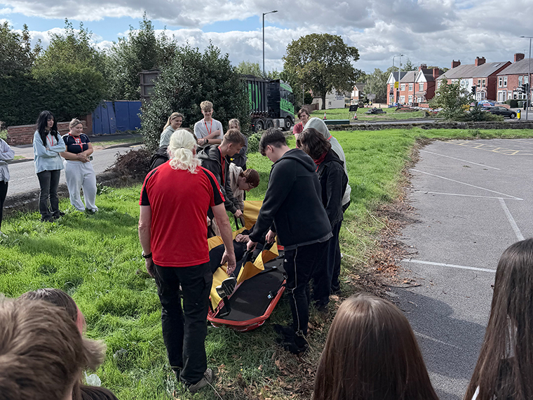 A man from Nottinghamshire Search and Rescue showing a group of people how to put someone on to a stretcher