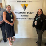 A sign that reads 'Welcome to Willmott Dixon Since 1852 Employer Academy' two people stood at each side of the sign